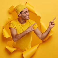 Man busting through paper wall pointing up