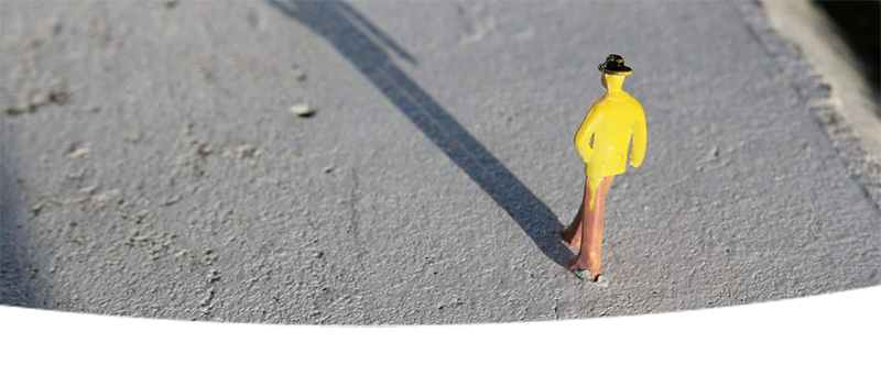 Small model of a man walking on concrete